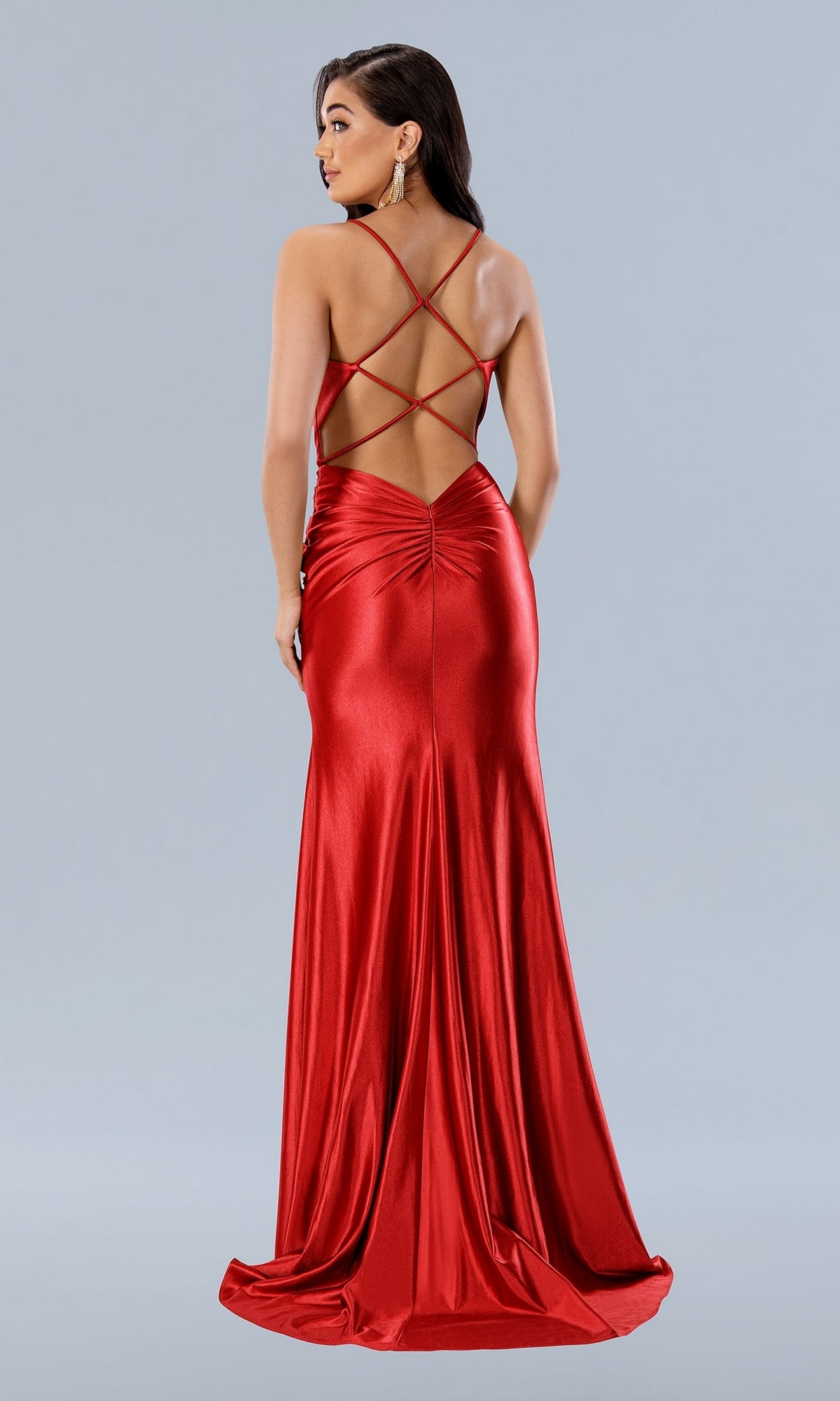 A woman models the Corset-Bodice Long Sweetheart Prom Dress 24108—a shiny, red, floor-length gown with a low open back and crisscross spaghetti straps—standing against a plain light gray background.